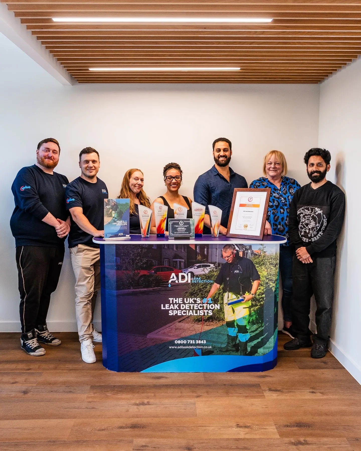 ADI team photographed together at their office with company awards